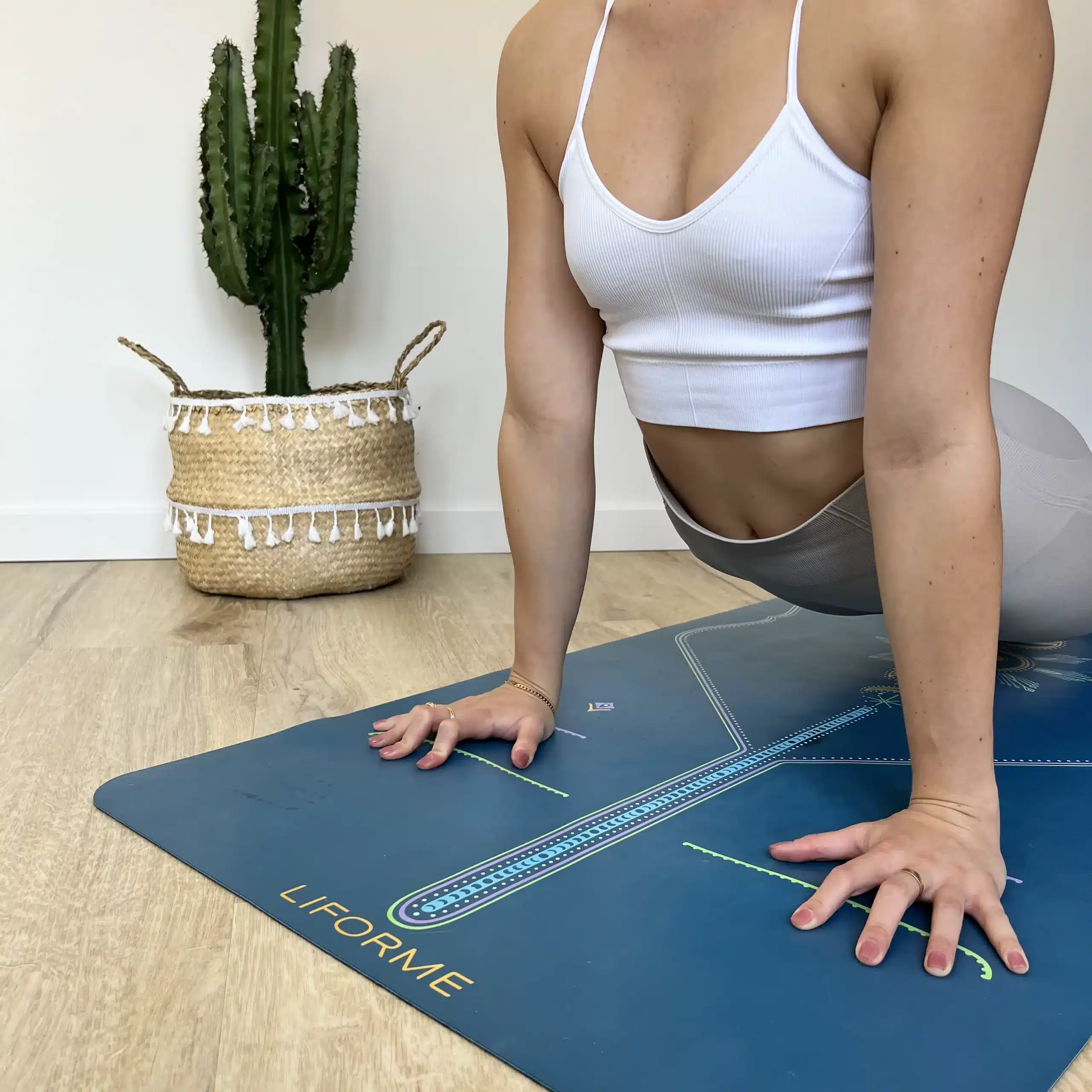 Une femme pratique le yoga sur un tapis avec un cactus en arrière-plan